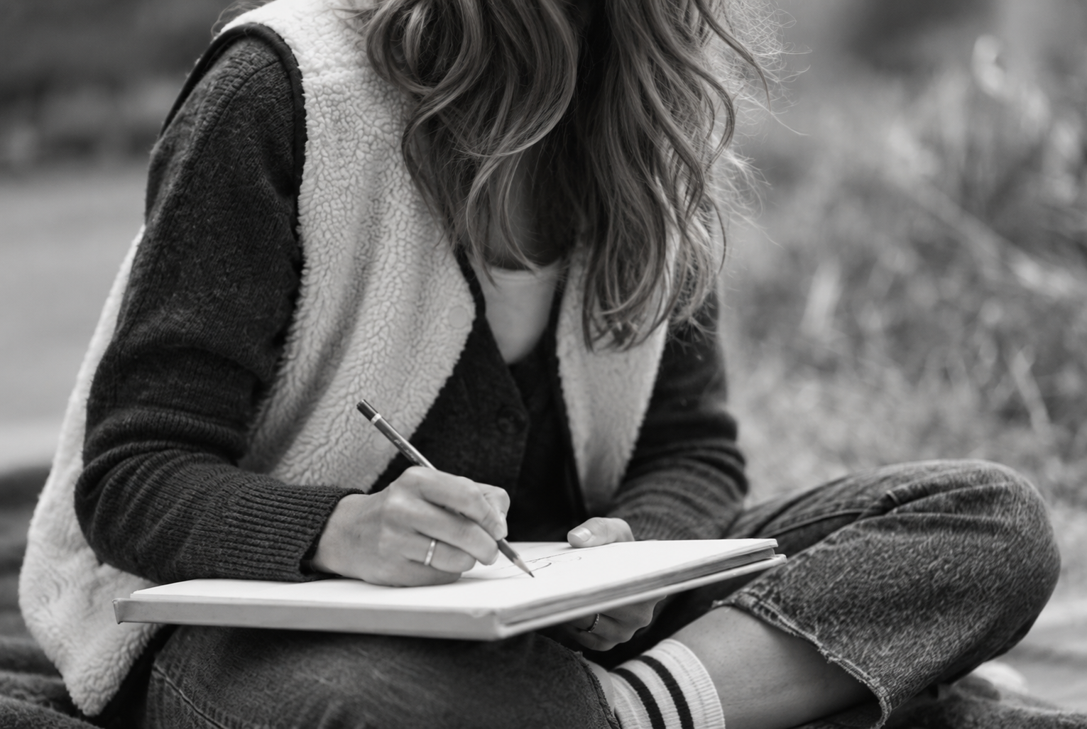 A woman writing in a sketchbook outdoors