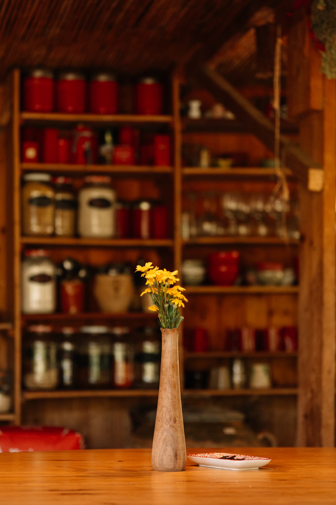 Yellow flowers in a wooden vase on a long table